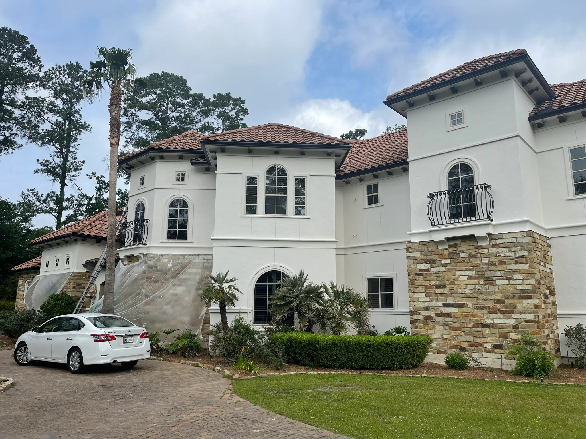 White Mediterranean home with clay tile roof, stone veneer, and paver driveway in Montgomery, TX