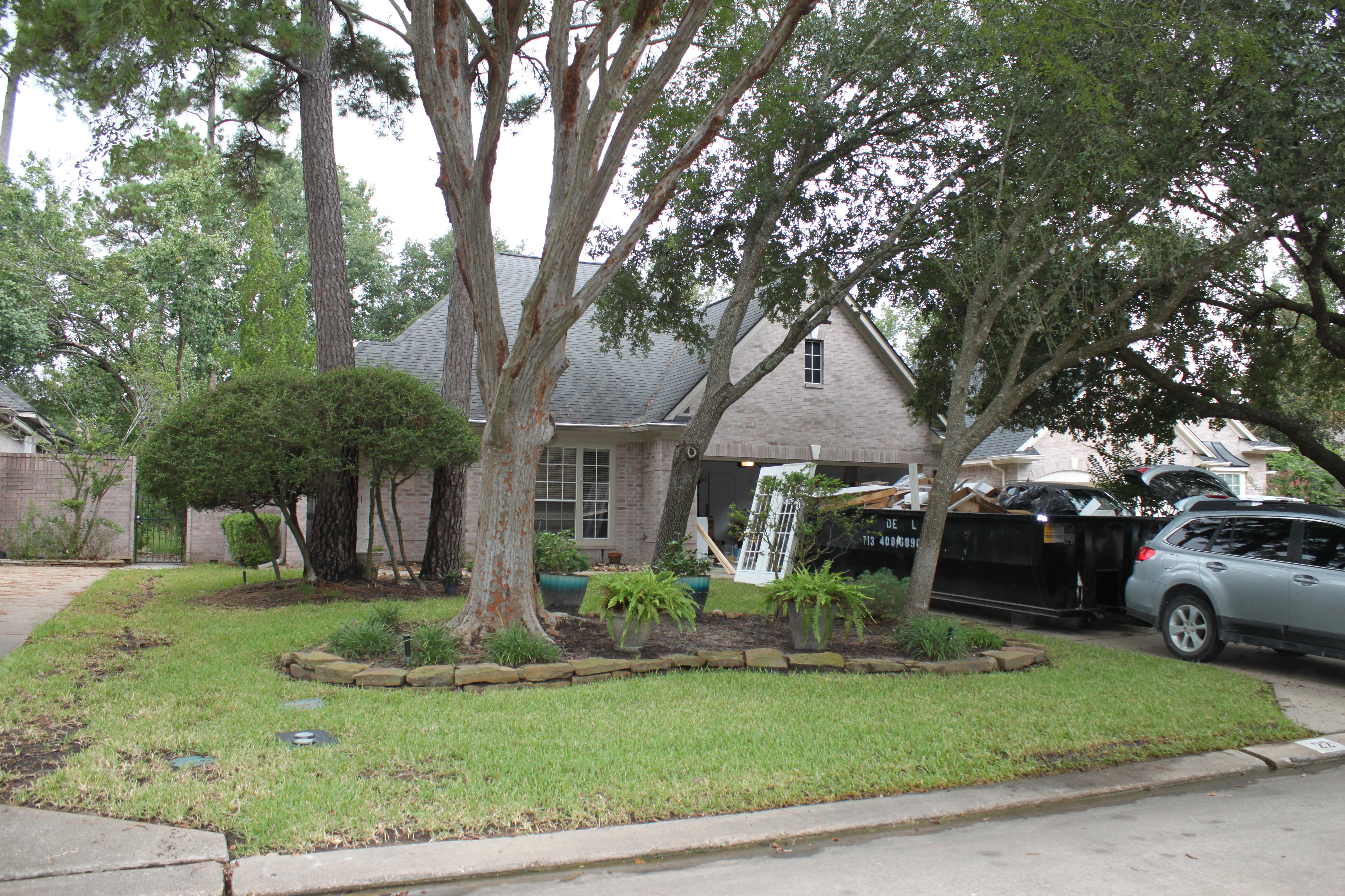 Front yard landscape bed with stone edging around mature trees and fresh mulch